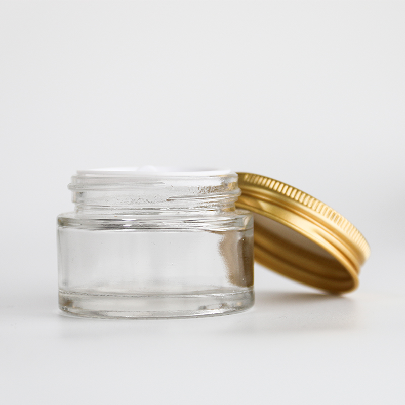 Leere, durchsichtige Glasbehälter, nachfüllbare Kosmetikfläschchen, Cremetiegel aus Glas mit Golddeckel