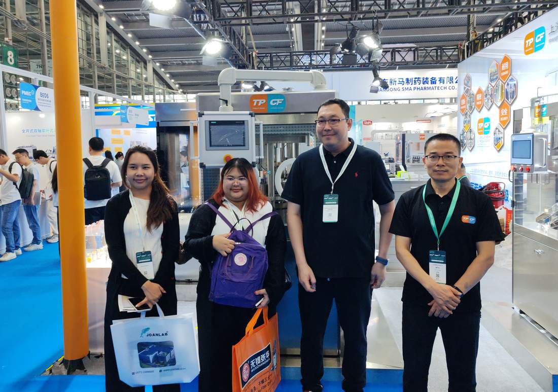 Visitors and the Shanghai Tablet Press team in front of pharmaceutical equipment