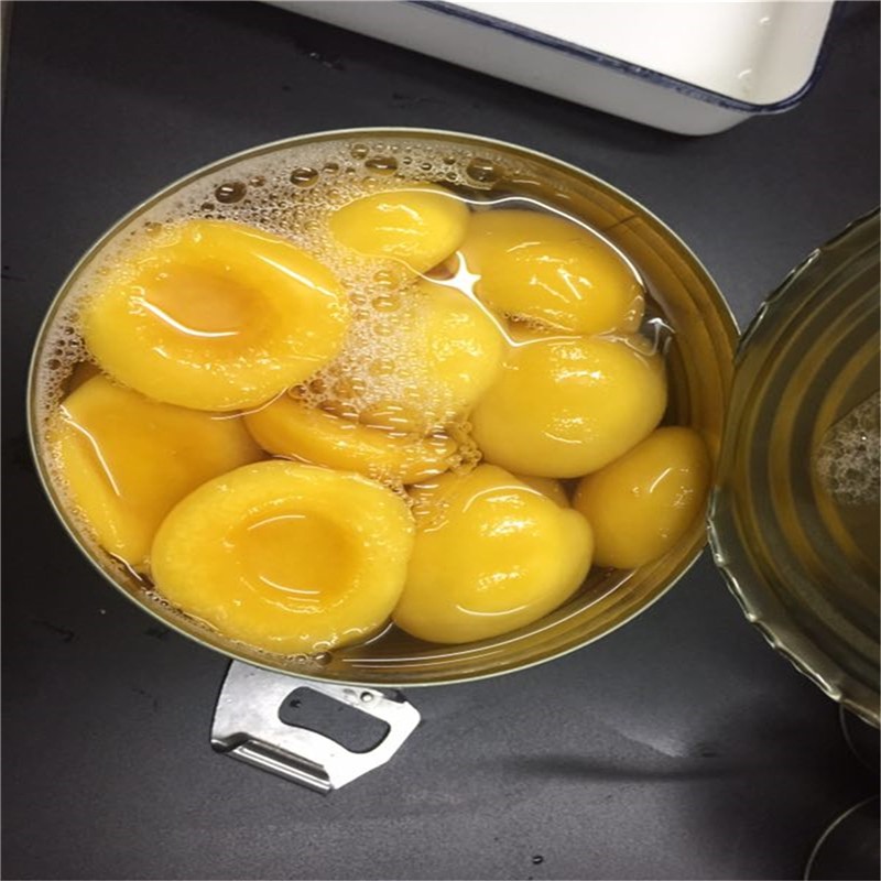 Metades de pêssegos amarelos enlatados em xarope claro