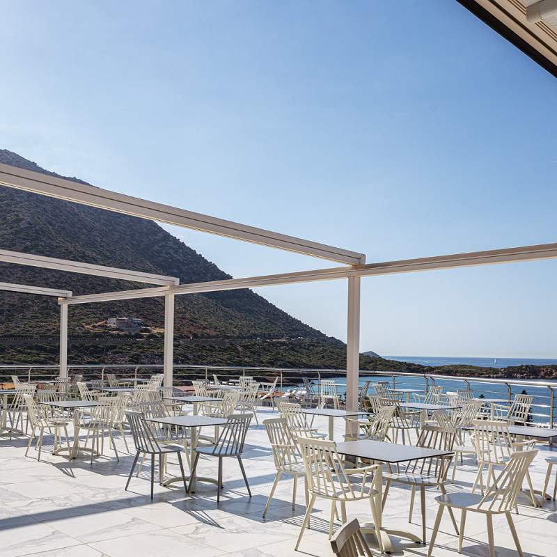 Chaises de salle à manger Windsor à dossier haut blanc en aluminium au restaurant grec de bord de mer