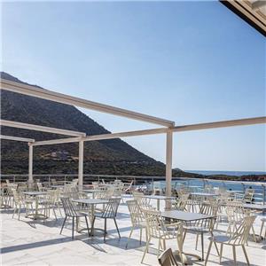 Aluminium witte Windsor-eetkamerstoelen met hoge rugleuning bij Grieks restaurant aan zee