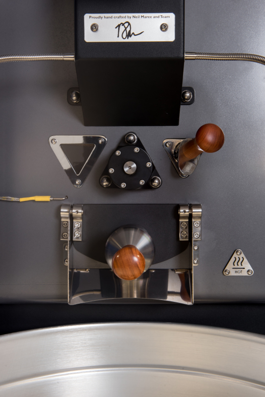 Máquina tostadora de café industrial con granos de café recién