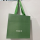 녹색 Kraft는 편평한 리본 손잡이를 가진 쇼핑 종이 봉지를 입습니다