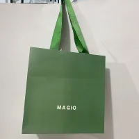 Les vêtements verts d'emballage chaussent les sacs en papier d'achats avec les poignées plates de ruban