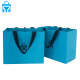 青い四角い底の花の布の靴の花束ショッピング包装紙袋