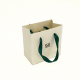Маленькая упаковка сумки для гольфа из белой подарочной бумаги, пригодной для вторичной переработки, с именной биркой, ручками из зеленой ленты для декоративной упаковки ювелирных изделий.