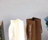 Wiederverwendbare weiße braune Kraftpapier-Einkaufstasche mit Blumenstrauß und Wein als Geschenk