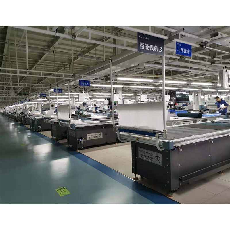 A large garment factory cutting area with rows of automated CNC cutting tables