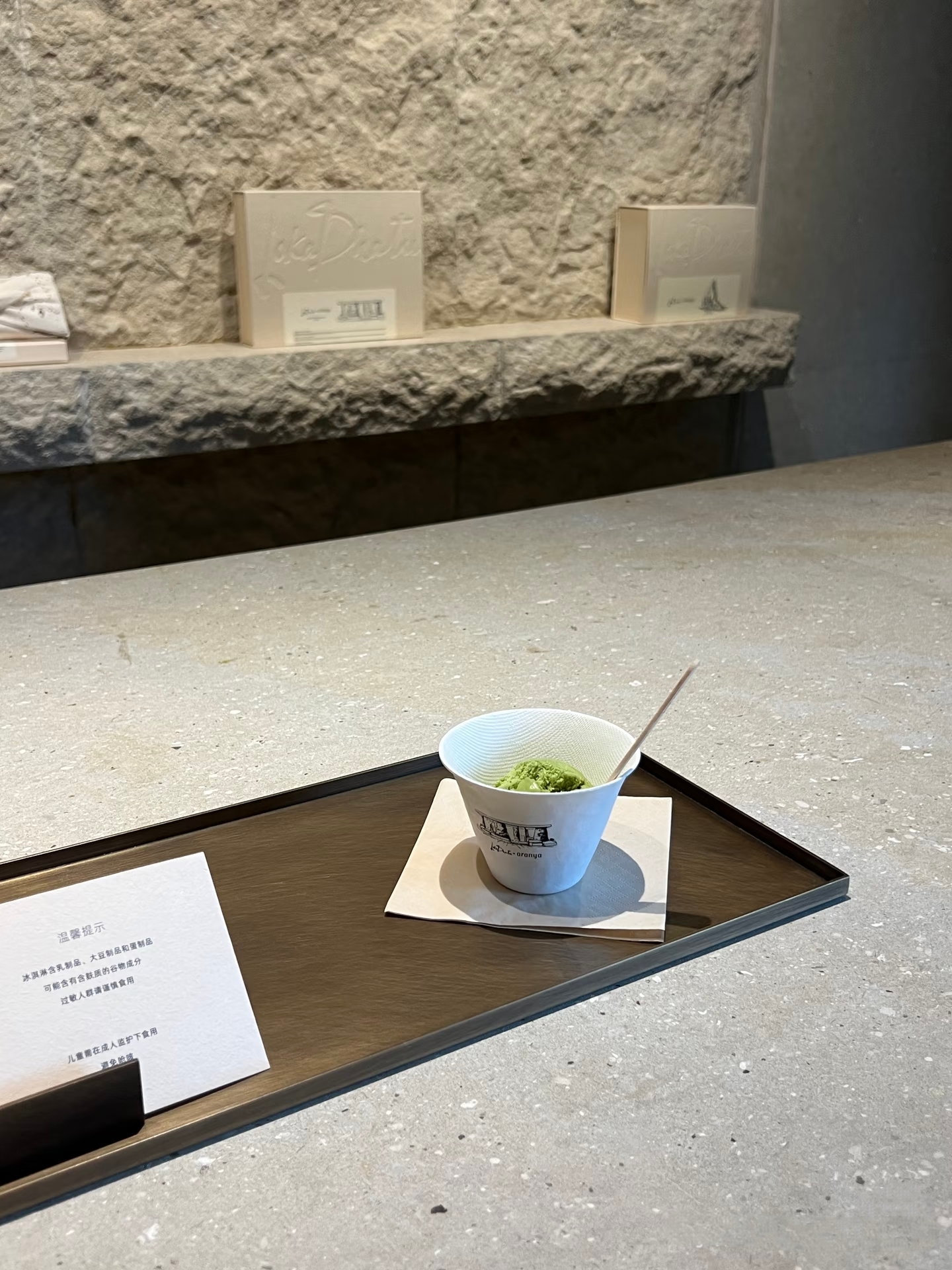 在喧嚣都市中，藏着这样一方疗愈天地。秦皇岛的“阿那亚露迦徒店”，以侘寂美学为笔，在带有白色斑点石质肌理的空间里，勾勒出自然与人文的交融。是一场嗅觉与视觉的双重疗愈。西班牙天然石材 “瓦尔塞金” 的粗犷纹理与白色斑点的自然肌理，如大地的质朴底色，而香氛的丝丝萦绕，似灵动的气息在石间穿梭。每一缕香气都在石材的质感中沉淀，每一块石材也因香气的晕染更显温润。于侘寂之境里，营造出既原始又雅致的感官秘境，让身心在自然与艺术的交融中，尽享松弛与治愈。