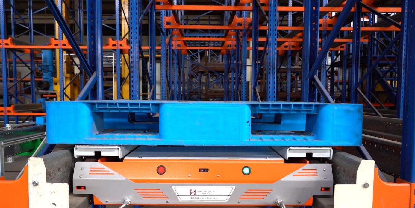 Four-way pallet shuttle lifting a pallet for automated storage retrieval