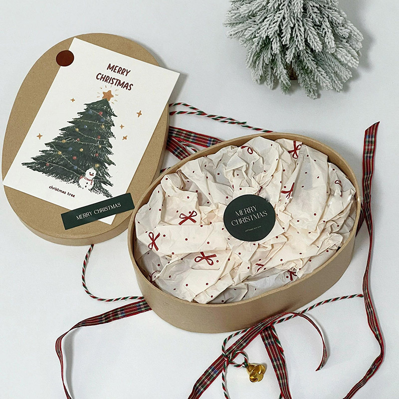 Scatola regalo rotonda personalizzata per Natale con carta velina e nastro.