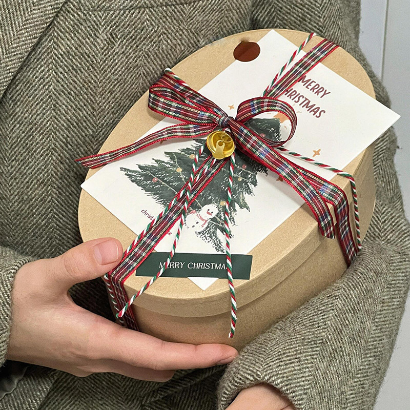Scatola regalo rotonda personalizzata per Natale con carta velina e nastro.
